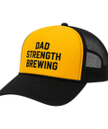 A yellow and black trucker-style cap with the words 'DAD STRENGTH BREWING' printed in black on the front panel, shown on a plain white background.
