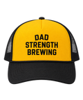 A yellow and black trucker hat with the words 'DAD STRENGTH BREWING' printed in black on the front panel, shown against a plain white background.