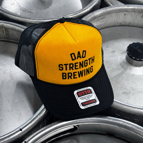 Yellow and black Dad Strength Brewing foam trucker hat with bold black logo, black mesh back, and curved black brim.